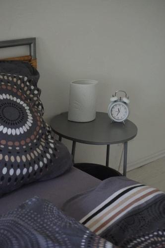 a alarm clock on a table next to a bed at Leuchtturmnest in Krummhörn
