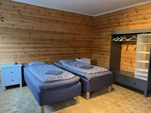 two beds in a room with wooden walls at Hook&Cup in Sorsele