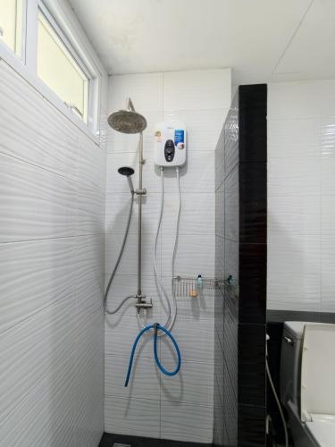 a shower with a blue hose in a bathroom at Home Valot Bed and Breakfast in Lan Saka