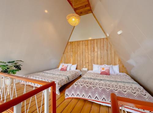two beds in a attic room with wooden floors at Griya Cabin 5 Dieng in Diyeng