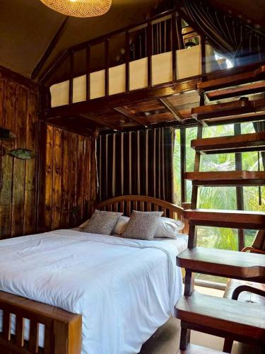 a bedroom with a white bed and a ladder at Cheewatra Farmstay Coconut House in Ban Tha Maphrao