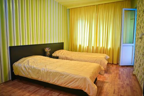 two beds in a hotel room with yellow walls at Apartment Elegance in Stara Zagora