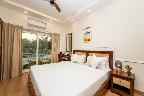 a bedroom with a large white bed and a balcony at Yellowstone Resort Arambol in Arambol