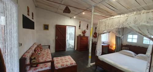 a bedroom with a canopy bed and a chair at Villa Culture in Ile aux Nattes