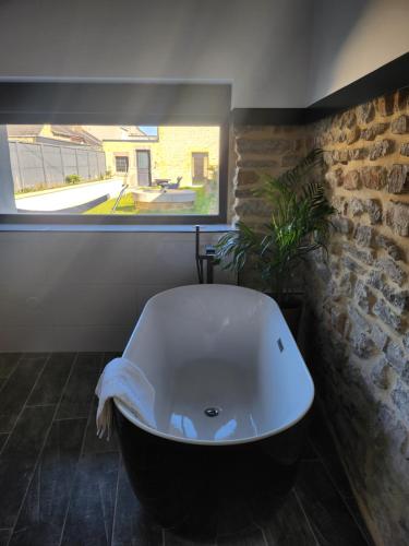 a bath tub in a bathroom with a window at L'Atypique - Piscine chauffée - Maison en Pierre - Espaces insolites in Floing