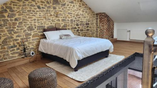 a bedroom with a bed and a stone wall at L'Atypique - Piscine chauffée - Maison en Pierre - Espaces insolites in Floing