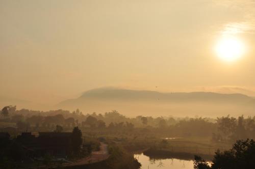 a misty sunrise with the sun rising over a river at Phurua Sanctuary Resort and Spa in Phu Rua