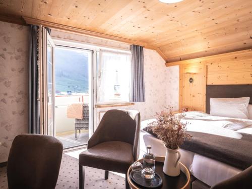 a bedroom with a bed and a chair and a window at Hotel Alpenblick in Weissbad
