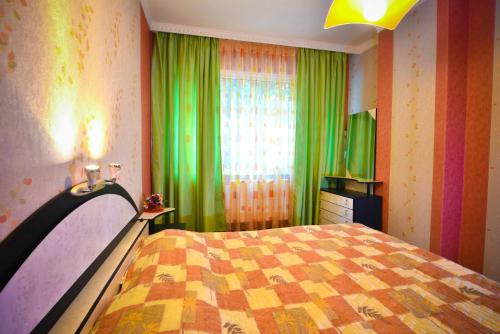 a bedroom with a bed and a window with green curtains at Apartment Elegance in Stara Zagora