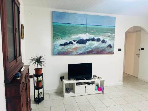 a living room with a tv and a painting on the wall at CASA BARBARA in Ventimiglia