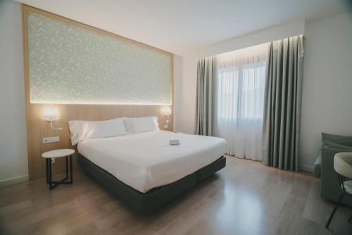 a hotel room with a large bed and a window at Sercotel Carlos III in Cartagena