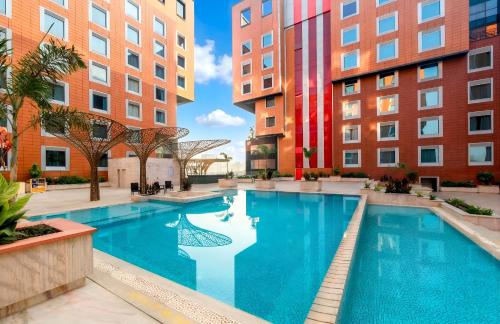a swimming pool in the middle of two tall buildings at The Orchid Hotel Hinjewadi Pune in Pune