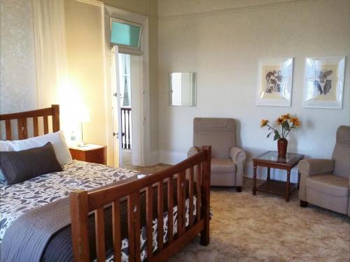 a bedroom with a bed and a couch and a chair at The Bank Guesthouse Glen Innes in Glen Innes