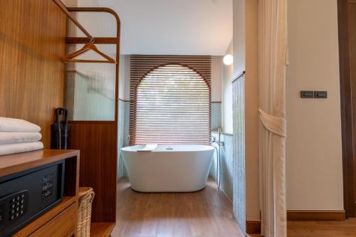 a bath tub in a bathroom with a window at Ploen Pirom in Lat Krabang