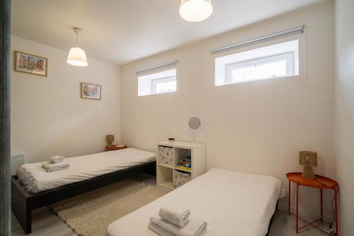 two beds in a room with two windows at Le Cocon Alsacien - Rez de chaussée - Parking privé in Ebersheim