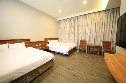 a hotel room with two beds and a tv at Kenting Four Season Villa in Hengchun