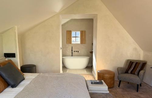 a bedroom with a bath tub and a bed and a chair at Roomer in Landen