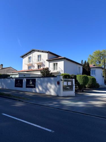 a white house with a white fence and a street at Les Criquets Hôtel & Spa in Blanquefort