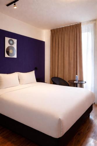 a hotel room with a large white bed and a window at ClapClap Hôtel Strasbourg in Strasbourg