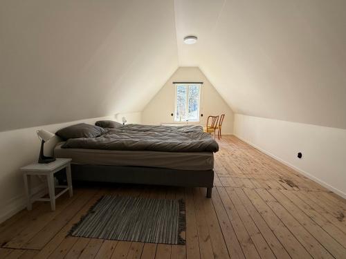 a bedroom with a bed on a wooden floor at Fiskarhuset - seaside cottage 4 pax in Sjöbo