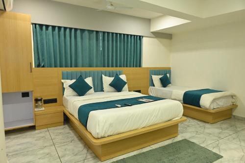 a hotel room with two beds and a window at Hotel Revanta Inn in Ahmedabad