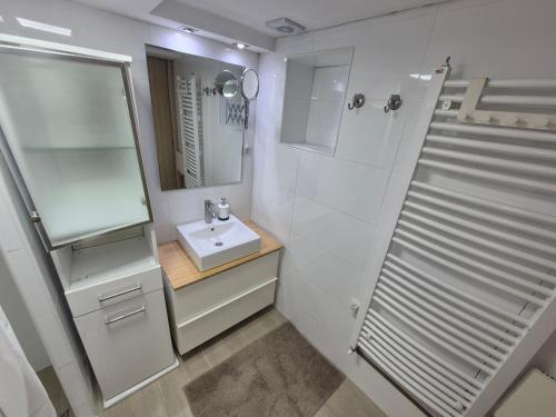 a white bathroom with a sink and a mirror at Panorama Apartment in Belgrade