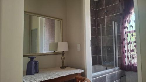 a bathroom with a mirror and a vase on a table at Melody Guest House in Centurion