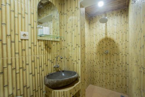 a bathroom with a stone sink and bamboo walls at Krisna Homestay in Canggu
