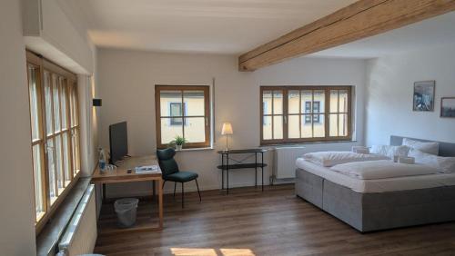ein Schlafzimmer mit Bett, Schreibtisch und Fenstern in der Unterkunft Kastanienbaum in Herzogenaurach