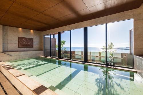 a swimming pool with a view of the ocean at Ishinoya Beppu - TKP Hotels & Resorts in Beppu