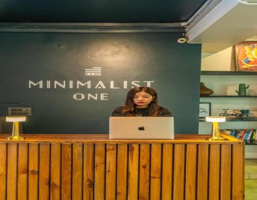a woman sitting at a counter with a laptop computer at Minimalist One Hauz Khas Village in New Delhi