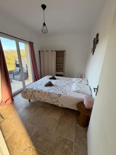 a bedroom with a bed and a large window at "Vigna d’Eugène" – T3 Piscine | by Efficios in Petreto-Bicchisano