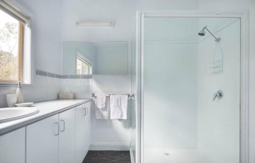 a white bathroom with a shower and a sink at Mereweather Estate Cottage in Dunkeld