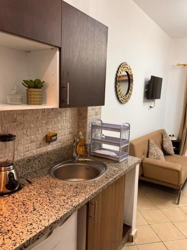 a kitchen counter with a sink and a couch at Studio moderne soleil piscine wifi à cabonegro in Tétouan