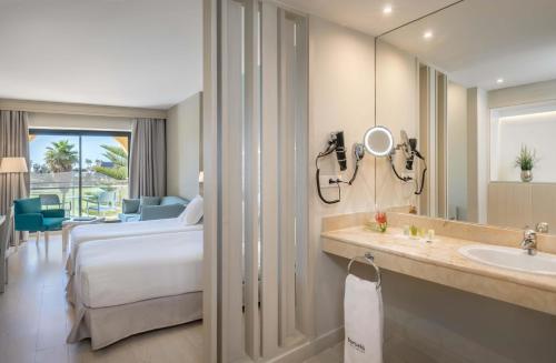 a hotel room with a bed and a sink and a mirror at Barceló Costa Ballena Golf & Spa in Costa Ballena
