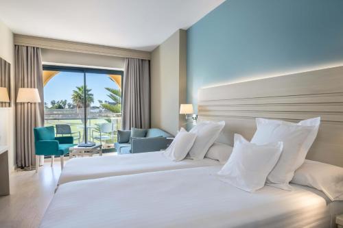 a hotel room with a large bed with white pillows at Barceló Costa Ballena Golf & Spa in Costa Ballena