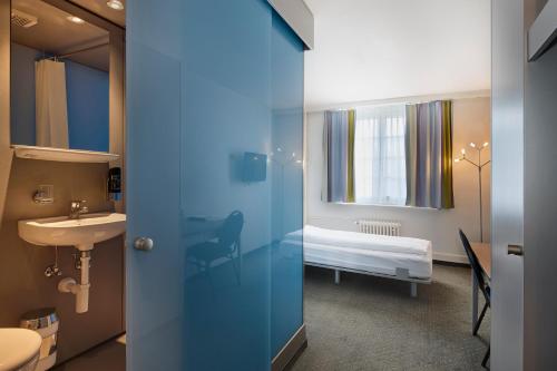 a bathroom with a sink and a bedroom with a bed at Hotel & Gasthaus Die Perle in Perlen