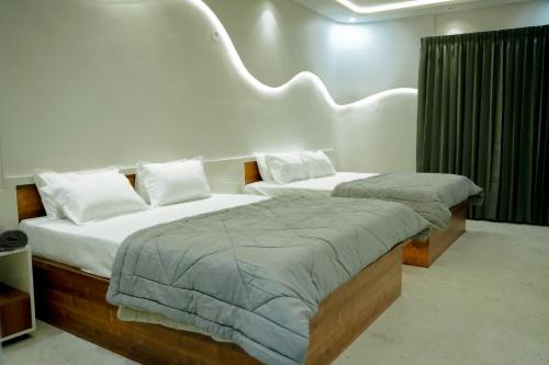 a bedroom with two twin beds with white pillows at Arthanaa Villa in Mysore
