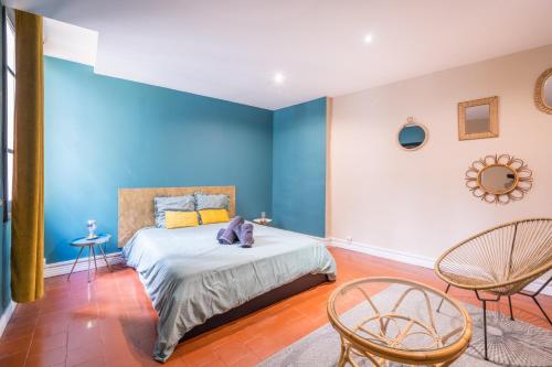 a bedroom with blue walls and a bed with chairs at L’Escapade Nîmoise - grand studio centre Nîmes in Nîmes
