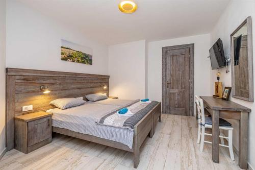 a bedroom with a large bed and a desk at Rustikalna kuća za odmor VILLA MARE in Kornić