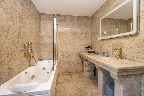 a bathroom with a bath tub and a sink and a bath tub at Rustikalna kuća za odmor VILLA MARE in Kornić