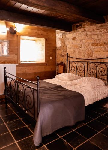 a bedroom with a black bed in a stone wall at Le Pays des Sources in Waimes