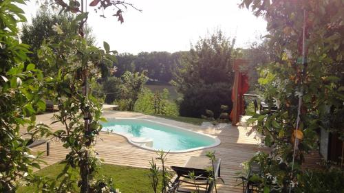 a swimming pool on a wooden deck in a garden at Timazen Lodges Agen Sud in Aubiac