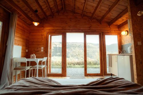 a room with a bed and a kitchen with a table at Deux Chalets face à la vallée in Chalezeule