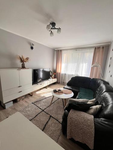 a living room with a leather couch and a table at Apart Konopnicka in Augustów