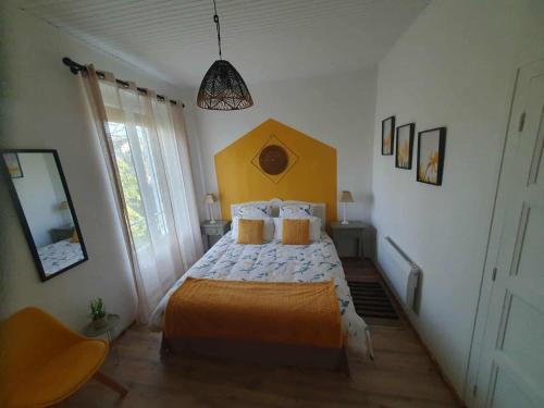 a bedroom with a bed with a yellow headboard at La Tulipe Périgourdine in Le Buisson de Cadouin