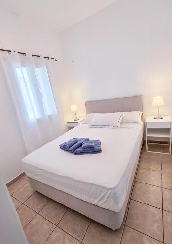 a bedroom with a white bed with towels on it at Panostria Apartments Sifnos in Sifnos