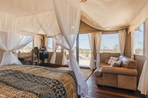 a bedroom with a bed and a couch at Ohorongo Tented Camp in Kaneb Pos