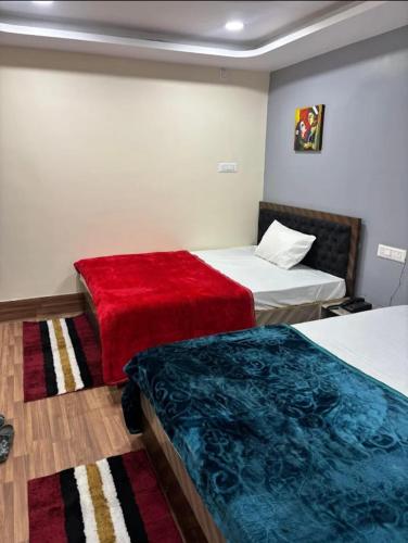 a hotel room with two beds and a red blanket at Hotel Magic Inn in Nagpur