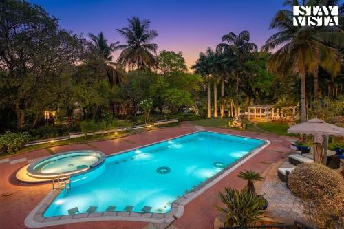 a swimming pool in a yard with a resort at StayVista at Ananta - Breakfast Included & Basketball Court in Bangalore